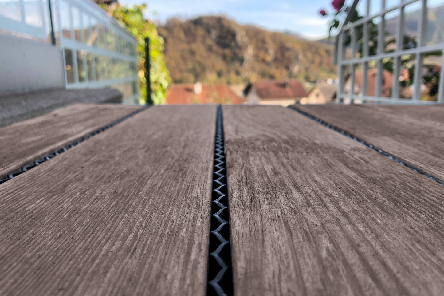 Ein Zick-Zack Terrassenfugenband auf einer Terrasse. Das Zick-Zack Fugenband ist luftdurchlässig und schützt die Fuge vor Verschmutzung. Nur das patentierte Zick-Zack Fugenband stellt die notwendige Belüftung der Unterkonstruktion sicher. Terrassenfugenband für Terrassendielen zur Selbstmontage. Dieses Fugenband verhindert zuverlässig, dass kleine Gegenstände in den Fugen von Terrassendielen verschwinden. Zick-Zack ist ideal auch zur Nachrüstung bestehender Terrassen. zick zack Band Fuge WPC Holzterrasse